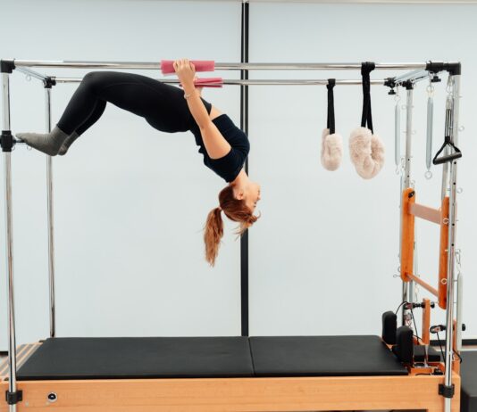 일상 속에서 필라테스, 건강한 몸과 마음을 위한 새 트렌드 a woman doing a handstand on a pivot machine